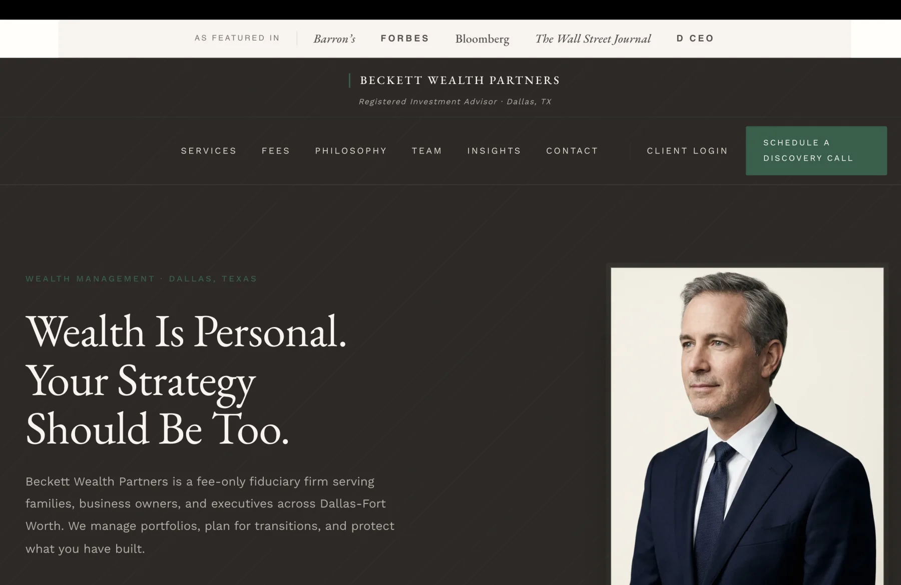 The home page of Beckett Wealth Partners, a Dallas fee-only fiduciary registered investment advisor. The very top of the page carries a cream AS FEATURED IN strip with five publication wordmarks set in mixed weights: Barron's in italic serif, FORBES in caps sans, Bloomberg in italic serif, The Wall Street Journal in italic serif, and D CEO in caps sans, separated by a small vertical divider after the AS FEATURED IN label. Beneath the strip, the page transitions to a deep charcoal-brown field with a subtle diagonal pinstripe overlay. A small green pipe and serif wordmark BECKETT WEALTH PARTNERS sits centered at the top of the dark field, with a calm italic tagline beneath in pale text reading Registered Investment Advisor, Dallas, TX. The horizontal navigation below the wordmark carries seven cream serif-caps links separated by generous letter spacing: SERVICES, FEES, PHILOSOPHY, TEAM, INSIGHTS, CONTACT, then a thin vertical divider, then CLIENT LOGIN, then a solid forest-green box reading SCHEDULE A DISCOVERY CALL in cream caps. The hero beneath fills the page with a split layout. The left half is on the same charcoal-brown field with a small green caps eyebrow reading WEALTH MANAGEMENT, DALLAS, TEXAS, then a tall cream serif headline that fills three lines: Wealth Is Personal. Your Strategy Should Be Too. A calm body paragraph in pale serif reads Beckett Wealth Partners is a fee-only fiduciary firm serving families, business owners, and executives across Dallas-Fort Worth. We manage portfolios, plan for transitions, and protect what you have built. Two CTAs sit beneath: a solid forest-green button reading SCHEDULE A CONSULTATION and a ghost green-bordered button reading OUR APPROACH. A stats row beneath the CTAs separated by thin vertical dividers reads 2003 FOUNDED, $540M ASSETS UNDER ADVISEMENT, Fee-Only FIDUCIARY, with the green italic numbers above small green-caps labels. The right half of the hero is a large editorial portrait of the founding partner: a silver-haired man in his fifties in a deep navy two-button suit, a pale blue dress shirt, and a navy patterned silk tie, photographed three-quarter-length from chest to head against a calm cream backdrop, looking slightly off-camera with a measured warm gaze. Beneath the portrait, an italic credit reads James Beckett, CFP, CFA above a green caps line FOUNDING PARTNER.