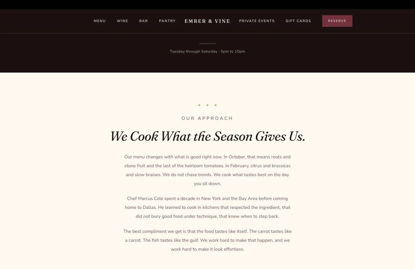 Approach section: a calm cream field with a centered three-diamond gold ornament, then a small burgundy eyebrow reading Our Approach, then a tall italic serif headline reading "We Cook What the Season Gives Us." Below, three paragraphs in centered body serif. Paragraph one reads "Our menu changes with what is good right now. In October, that means roots and stone fruit and the last of the heirloom tomatoes. In February, citrus and brassicas and slow braises. We do not chase trends. We cook what tastes best on the day you sit down." Paragraph two reads "Chef Marcus Cole spent a decade in New York and the Bay Area before coming home to Dallas. He learned to cook in kitchens that respected the ingredient, that did not bury good food under technique, that knew when to step back." Paragraph three reads "The best compliment we get is that the food tastes like itself. The carrot tastes like a carrot. The fish tastes like the gulf. We work hard to make that happen, and we work hard to make it look effortless."