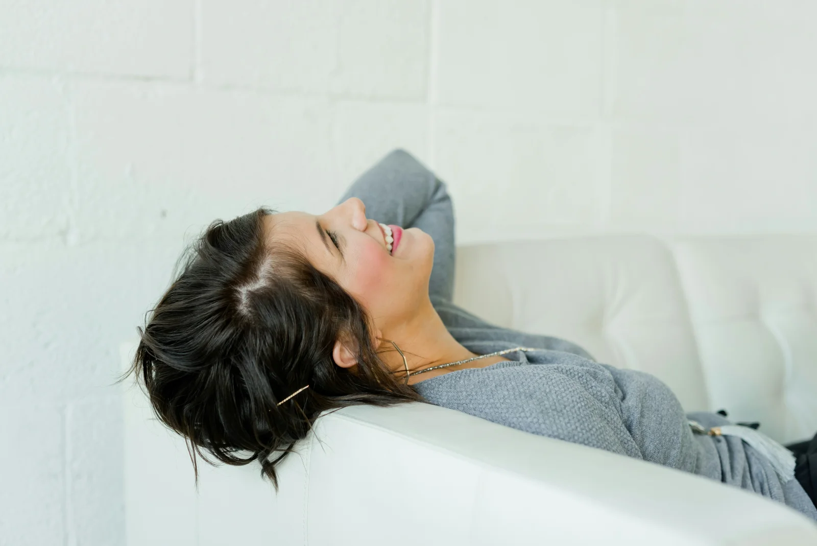A patient in unguarded laughter on a soft couch, the visual argument that the perinatal patient who keeps treating gets through